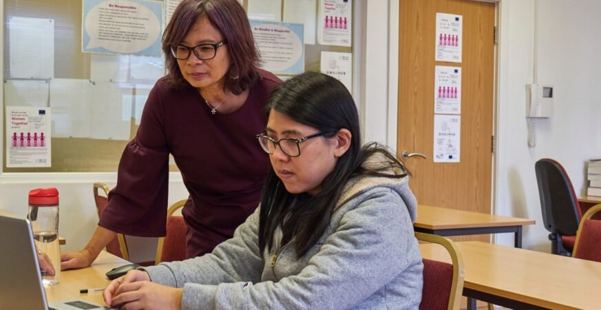 A woman showing a woman something on the laptop scaled